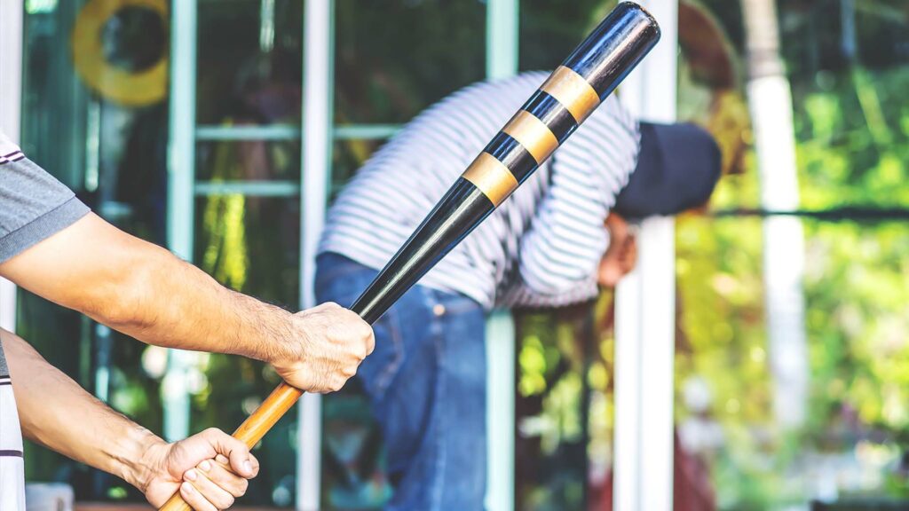 Man swinging a bat in the foreground with a man doubled over in the background