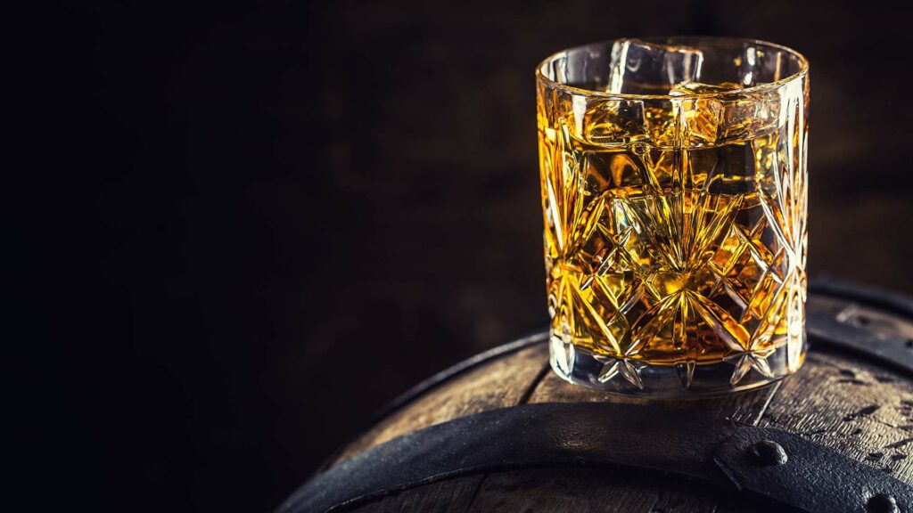 Closeup of crystal highball glass sitting on a barrel