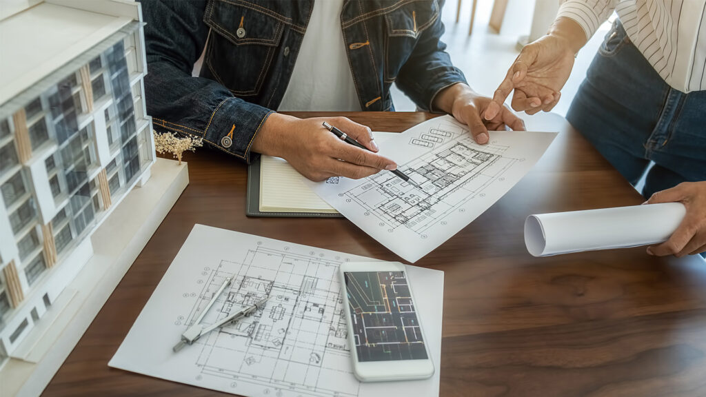 Overhead view of 2 people reviewing architect plans