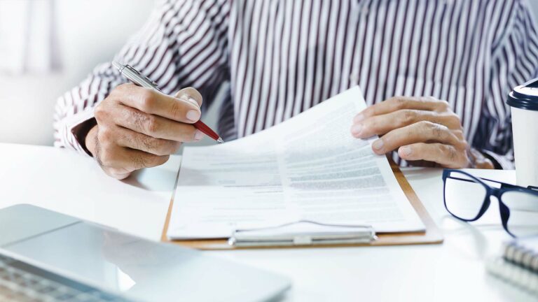 Businessman reviewing document report and key decisions.